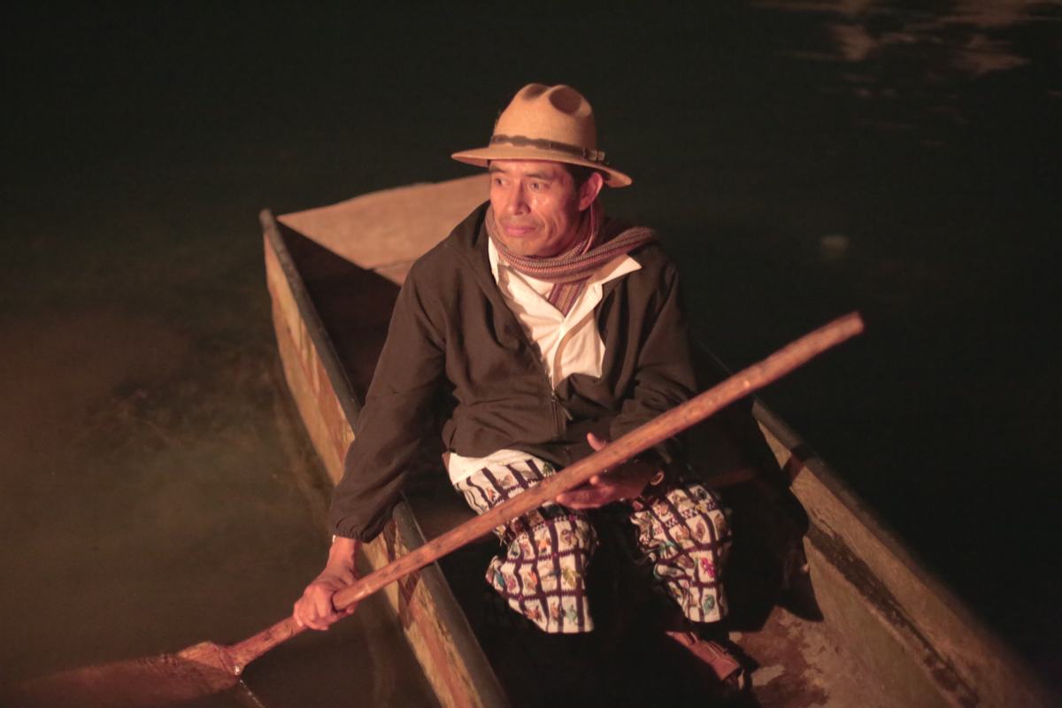 A man paddles a wooden canoe at night