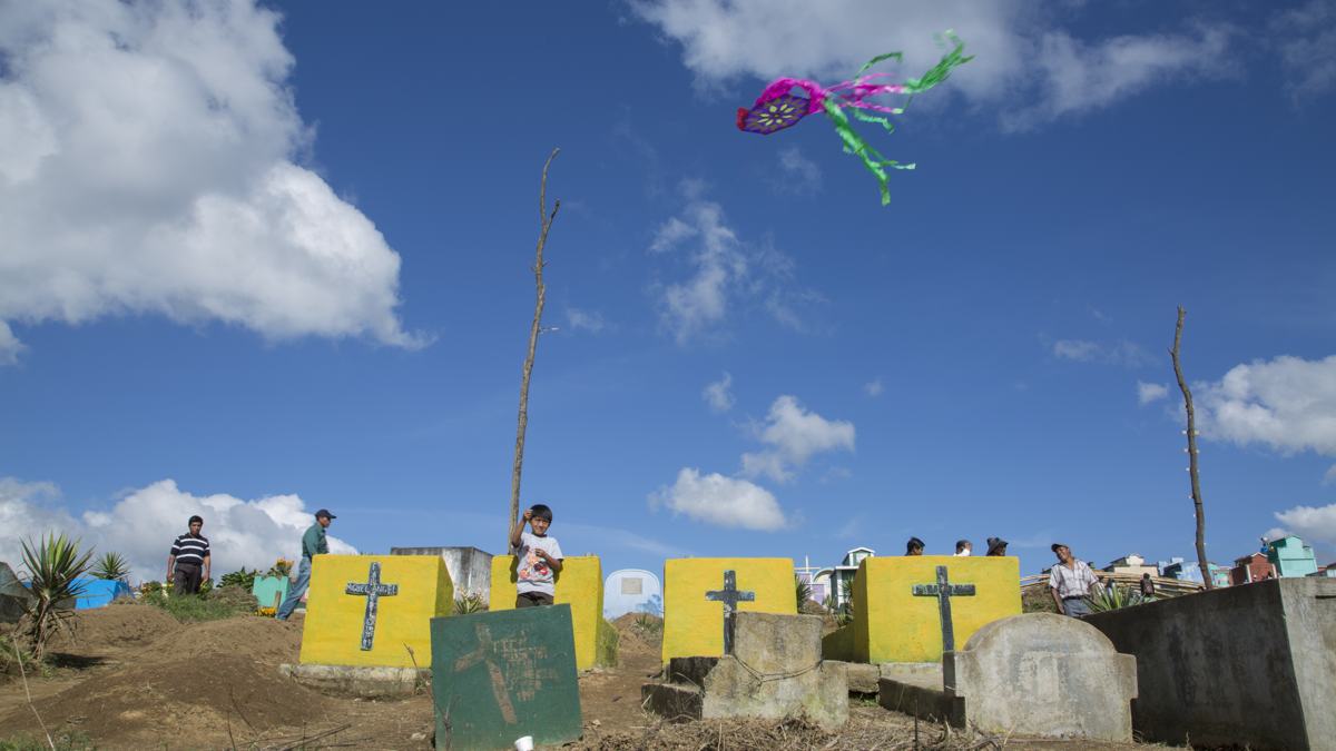 A boy flies a kite above painted graves