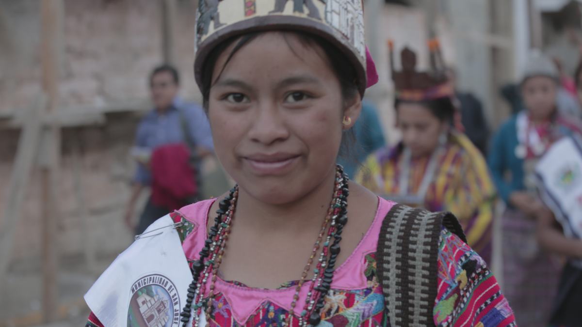 A young woman in a ceremonial headdress smiles