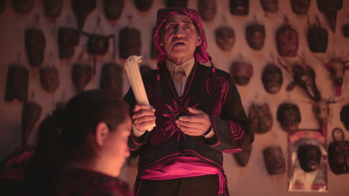 An elder before a wall of ceremonial masks