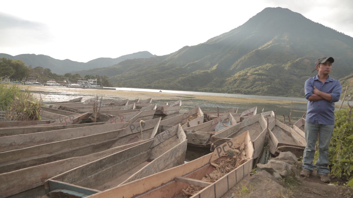Canoes on a lakeshore beneath a volcano