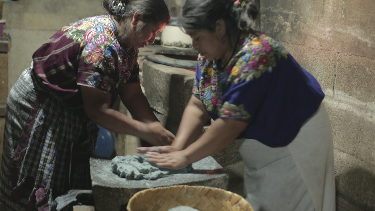 Two women grind maize dough on a stone metate