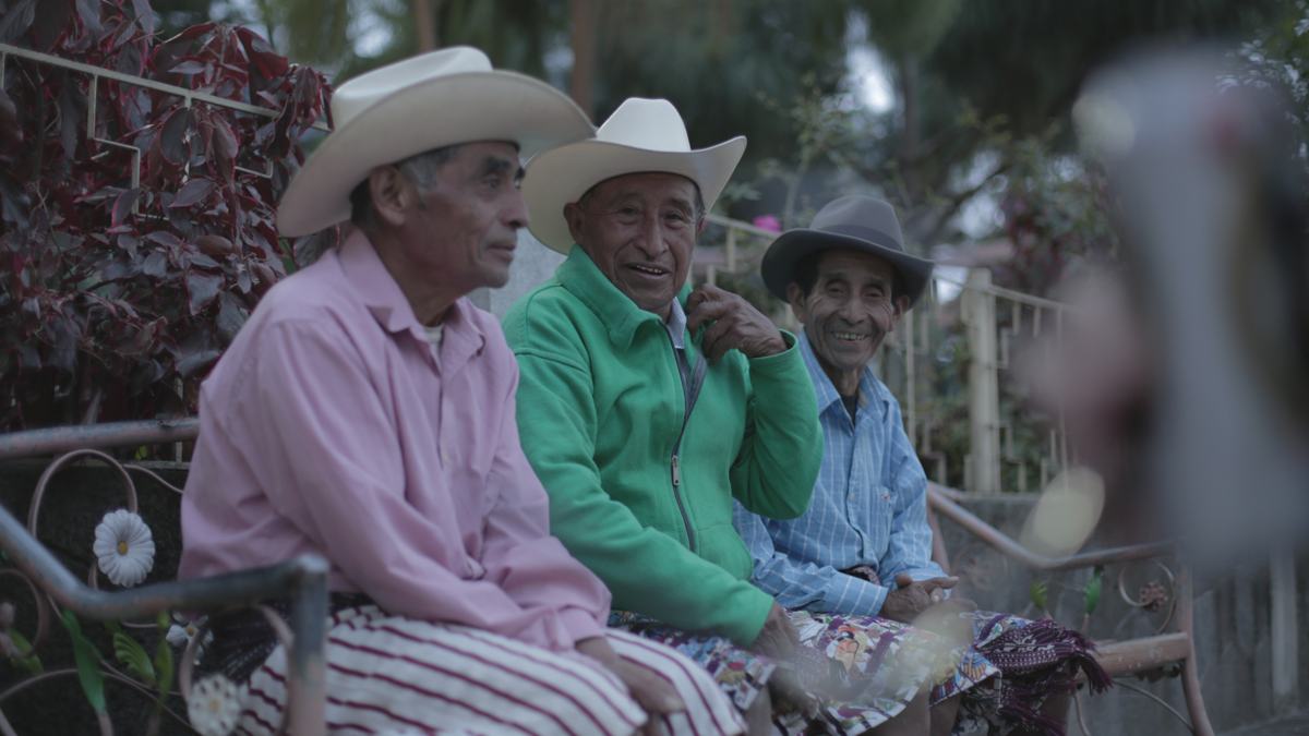 Three elders laughing on a bench