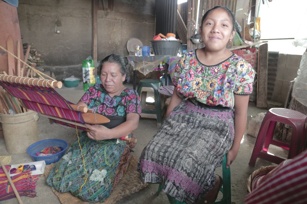 A weaver at her backstrap loom beside her daughter
